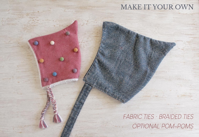 May include: A dusty rose bonnet with multicolored felt pom-poms and braided ties, alongside a charcoal gray bonnet with fabric ties. The text reads MAKE IT YOUR OWN, FABRIC TIES, BRAIDED TIES, and OPTIONAL POM-POMS.
