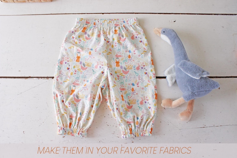 May include: A pair of white pants with an elastic waistband and cuffs, featuring a colorful pattern of small rabbits, flowers, and abstract shapes, accompanied by a plush grey goose toy. The text at the bottom reads: MAKE THEM IN YOUR FAVORITE FABRICS.