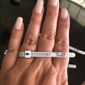 May include: White plastic ring sizer with numbers 5 through 17 and an arrow pointing to the number 7. The text "PAT. PEND. 9101693" is printed on the sizer.