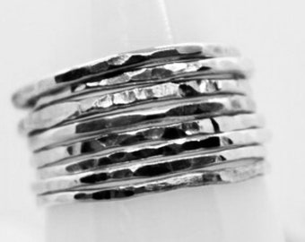 May include: A set of silver hammered stacking rings. The rings are thin and delicate, and they are stacked on top of each other to create a unique and stylish look.