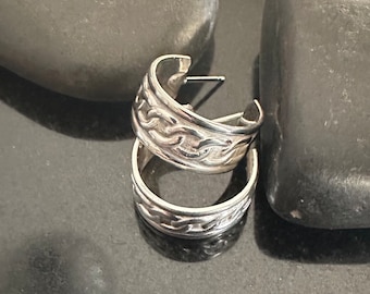 May include: A pair of silver hoop earrings with a braided design.