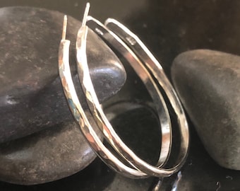 May include: A pair of silver hoop earrings with a hammered texture. The earrings are simple and elegant, and would make a great gift for any occasion.