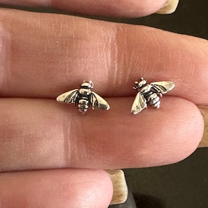 May include: A pair of silver bee stud earrings. The bees are detailed with wings and antennae.