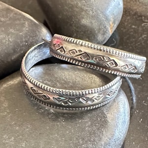 Op de afbeelding: Een paar zilveren creolen met een geometrisch patroon. De oorbellen zijn gemaakt van metaal en hebben een glanzende afwerking.