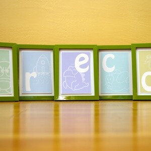 K&ouml;nnte beinhalten: F&uuml;nf gr&uuml;ne Bilderrahmen mit wei&szlig;en Buchstaben, die das Wort "greco" in einer verspielten Schriftart buchstabieren. Jeder Rahmen hat einen andersfarbigen Hintergrund und eine einfache Illustration im Inneren.