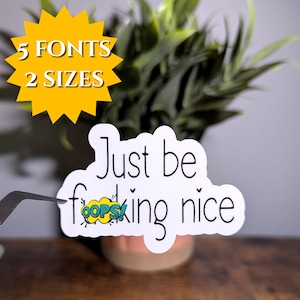 May include: A white sticker with the text "Just be f**king nice" in a handwritten font. The word "f**king" has a comic book style "OOPS" bubble. A yellow starburst graphic reads "5 FONTS 2 SIZES".