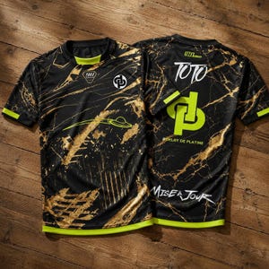 May include: A black short-sleeve jersey with a gold marble pattern and neon green accents. The front features a logo and a graphic. The back displays the text TOTO, a large neon green logo, the hashtag #DELAY DE PLATINE, and MISE A JOUR.