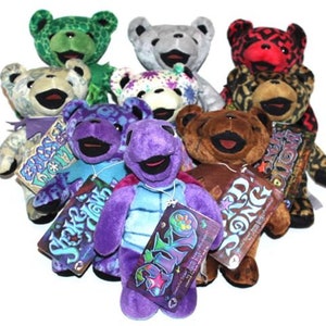 May include: A collection of nine colourful plush teddy bears with different patterns and designs. Each bear has a tag with a unique name and design. The bears are arranged in a circle, with the tags facing outwards.