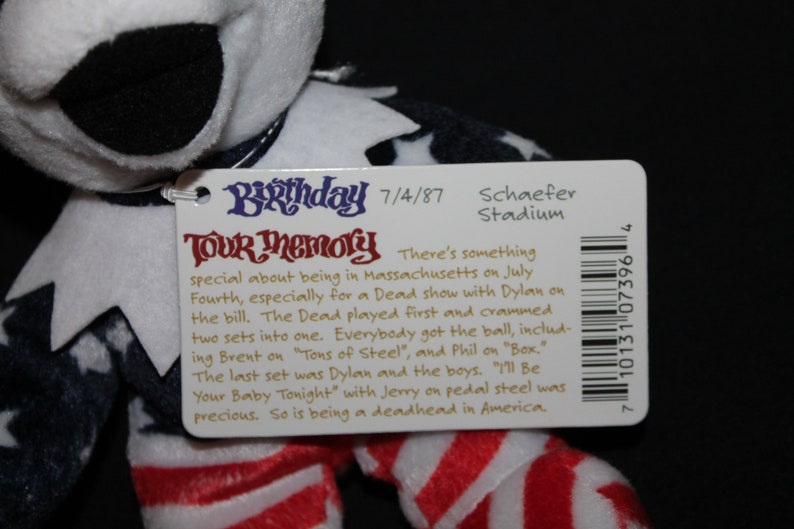 May include: A white, red and blue plush toy with a tag that reads "Birthday Tour Memory" and includes details about a concert on 4th July 1987 at Schaefer Stadium in Massachusetts. The tag also includes a barcode.
