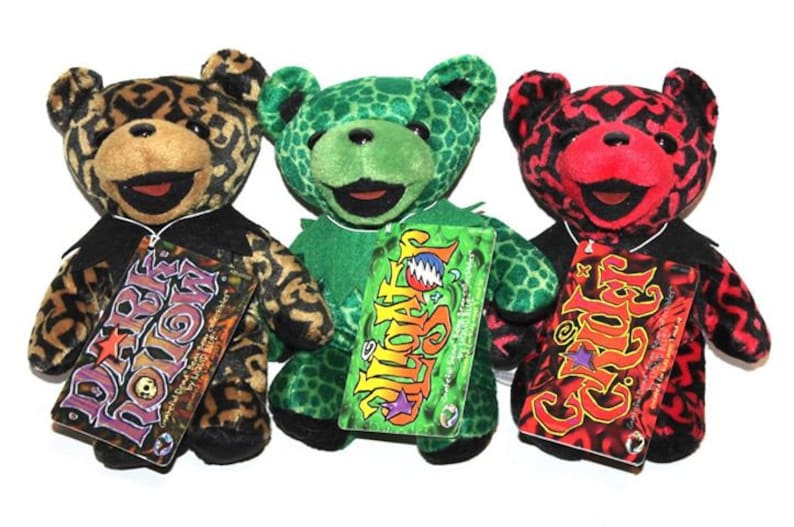 May include: Three plush teddy bears with different patterned fur. The bears are wearing black collars and have tags that say "Dark Star", "Steal Your Face", and "Grin" with a star.