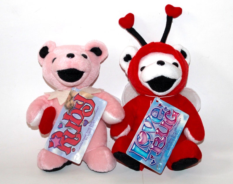Puede incluir: Dos osos de peluche, uno rosa con un coraz&oacute;n y el texto "Ruby" en la etiqueta, y otro rojo con alas y el texto "Love Bug" en la etiqueta.