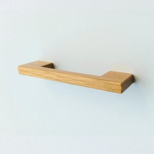 Puede incluir: Un tirador de armario de madera de color marrón claro con forma rectangular.