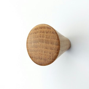 May include: A wooden knob with a rounded top and a tapered bottom. The knob is made of light brown wood with a natural grain pattern.