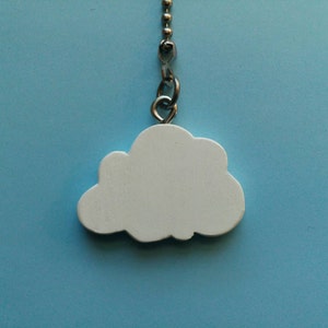 Può includere: Un tirante per ventilatore a soffitto a forma di nuvola bianca su una catena di perline argentata. La nuvola è realizzata in un materiale bianco pieno e pende su uno sfondo azzurro. La catena è attaccata alla nuvola con un piccolo anello di metallo.