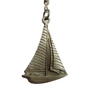 May include: A silver sailboat charm with a detailed design. The charm is attached to a silver chain.