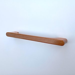 May include: A wooden cabinet pull with a rounded rectangular shape and a smooth, natural finish.