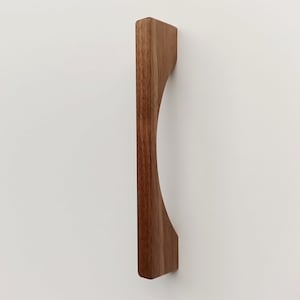 May include: A wooden cabinet door pull with a curved design. The pull is made of dark brown wood and has a smooth finish.