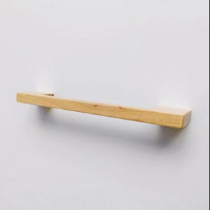 Könnte beinhalten: Ein Handtuchhalter aus Holz mit natürlicher Oberfläche. Der Halter ist an einer weißen Wand montiert.