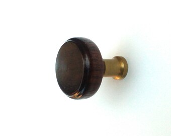 May include: A round, dark brown wooden cabinet knob with a brass base. The knob has a smooth, polished finish and is set against a white background. This hardware is suitable for drawers, cabinets, and other furniture.