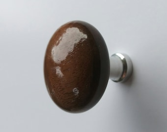May include: A wooden cabinet knob with a polished, oval-shaped head in a rich brown hue. The knob is attached to a silver-colored metal base. This hardware is suitable for drawers and cabinets.