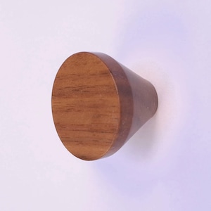 May include: A wooden cabinet knob with a circular, flat top and a conical body. The knob is made of light brown wood with visible grain, and the body is a darker brown. Suitable for use on cabinets or drawers.