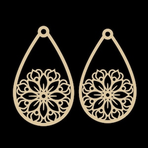 May include: A pair of teardrop-shaped earrings with a floral design cut out of a light tan material. The earrings have a small loop at the top for hanging and a detailed flower pattern in the lower half.