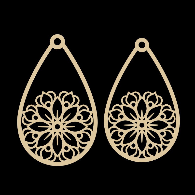 May include: A pair of teardrop-shaped earrings with a floral design cut out of a light tan material. The earrings have a small loop at the top for hanging and a detailed flower pattern in the lower half.