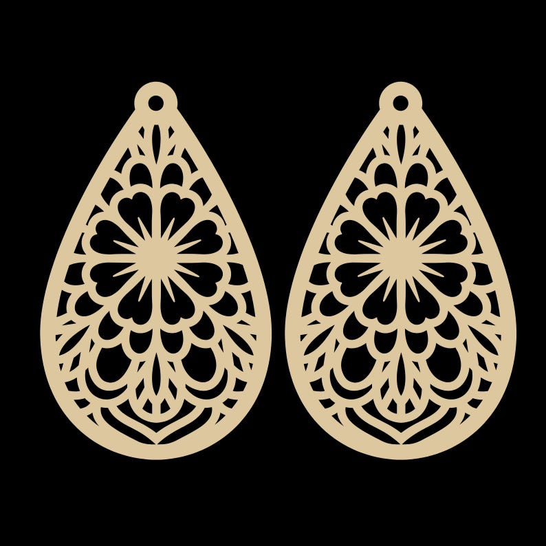 May include: Two beige teardrop-shaped earrings with intricate floral cut-out designs. Each earring features a central circular pattern surrounded by heart-shaped elements and delicate, curved lines. The earrings have a small hole at the top for attachment.