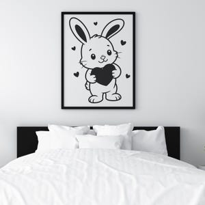 K&ouml;nnte beinhalten: Schwarz gerahmter Druck mit einem Cartoon-Hasen, der ein schwarzes Herz h&auml;lt. Der Hase ist wei&szlig; mit schwarzen Umrissen und Details. Kleine schwarze Herzen sind um den Hasen verstreut.