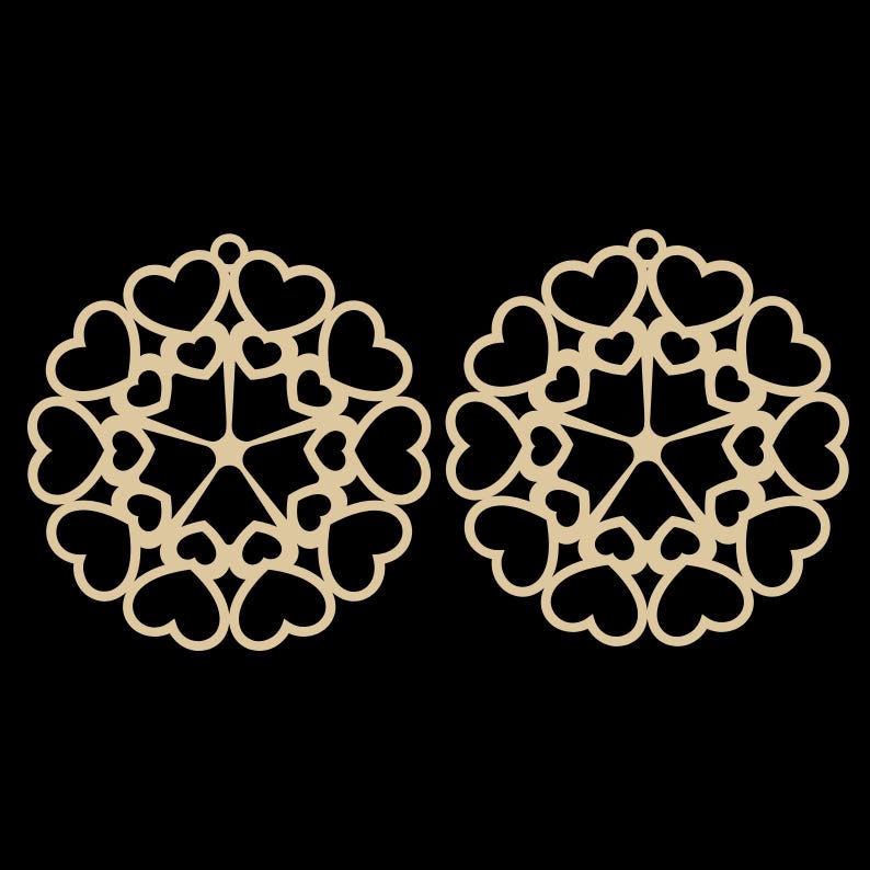 May include: Two laser-cut wooden ornaments, each featuring a circular design composed of heart shapes. The ornaments are a light tan color and have a small hole at the top for hanging. The background is solid black.