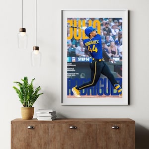 Puede incluir: Un póster enmarcado con el jugador de béisbol Julio Rodríguez en acción, vistiendo un uniforme azul y amarillo con el número 44. El póster incluye el texto "Julio Rodríguez, Novato del Año 2022" y el logo de los Marineros de Seattle.