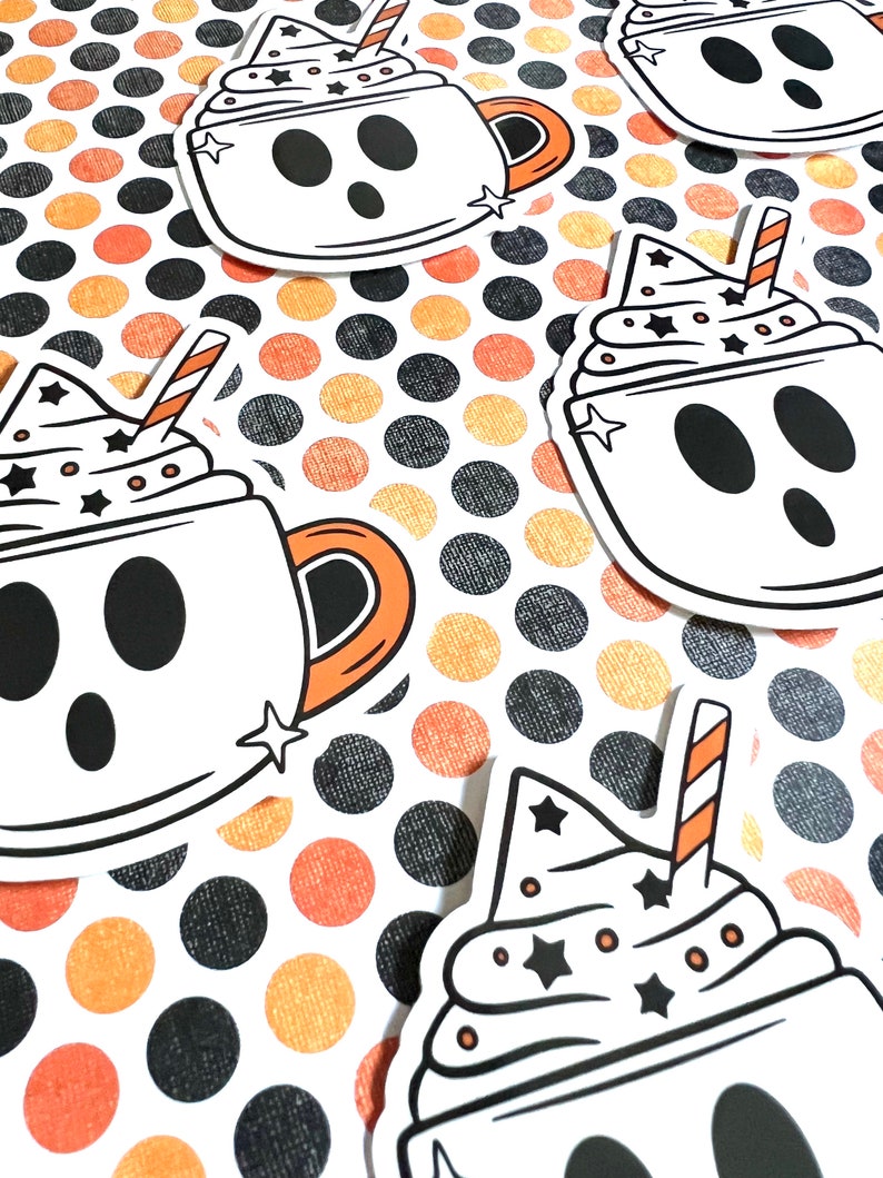 May include: Four white ghost-shaped mugs with black eyes and mouths, filled with white whipped cream and topped with a red and white striped straw and black stars. The mugs are on a background of orange and black polka dots.