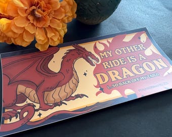 Puede incluir: Un dragón rojo con detalles amarillos y llamas se representa sobre un fondo amarillo y naranja. El texto dice "Mi otro medio de transporte es un dragón (...así que aléjate de mi cola)".