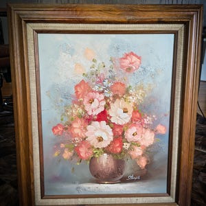 May include: Oil painting of a floral arrangement in a bronze vase, set against a light blue background. The flowers are in shades of pink, red, and white, with a wooden frame. Signed "Stemple".
