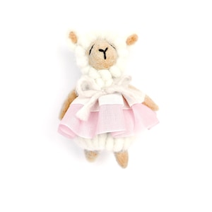 May include: A handmade white and tan llama doll wearing a pink tutu and a white bow. The llama has a fluffy white head and ears, with a tan face and limbs. The doll is standing upright against a white background.