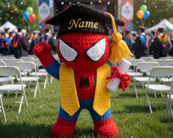 May include: A crocheted Spider-Man figure in a graduation cap and gown, holding a diploma. The cap has the name "Name" on it. The figure is red, blue, and yellow, standing on green grass with a graduation ceremony in the background.