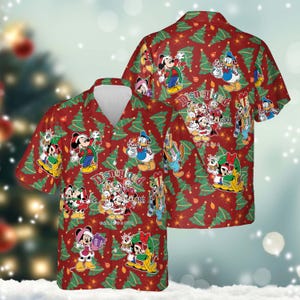 Puede incluir: Camisa roja con botones con un estampado festivo con personajes de Disney, árboles de Navidad y el texto "Disneyland 1955 California". La camisa tiene mangas cortas y cuello blanco. El diseño incluye Mickey Mouse, Pato Donald y otros personajes clásicos.