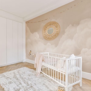 May include: A white crib with a plush white rug and a giraffe toy in a nursery. The wall features a cloud mural and a round, woven mirror. A pink blanket is draped over the crib.