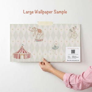 May include: A large wallpaper sample with a circus theme. The design includes an elephant on a pedestal, a bear riding a bicycle, a circus tent, and a ballerina. The background is a light green diamond pattern with gold stars. The sample is 76 x 48 cm.