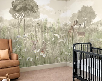 May include: A wall mural featuring a forest scene with deer, rabbits, butterflies, and wildflowers in muted green and beige tones. The mural covers two walls in a room containing a black crib, a brown armchair, and wooden toy blocks on the carpet.