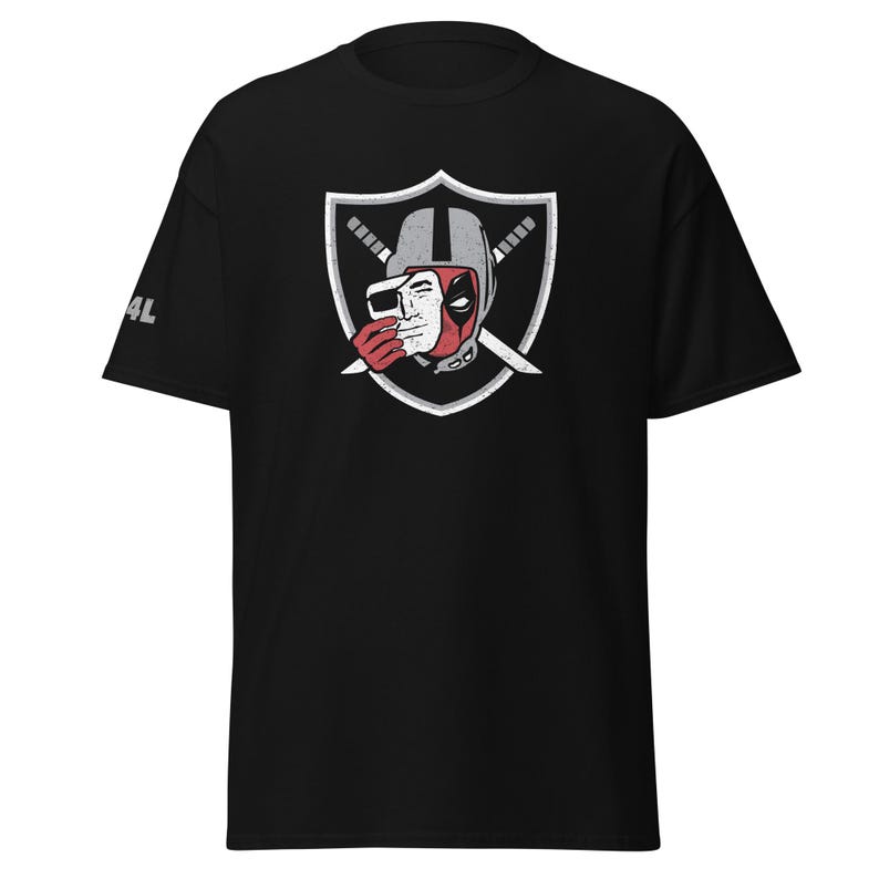 May include: A black short-sleeve t-shirt featuring a graphic on the chest of a shield with two crossed swords. Inside the shield is a character wearing a helmet and holding a white mask over their face. The text 4L is printed on the right sleeve.