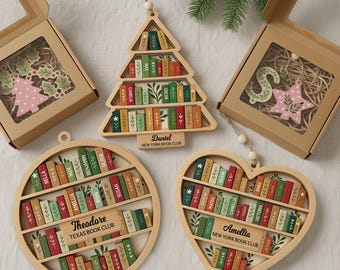 Könnte beinhalten: Weihnachtsschmuck aus Holz in verschiedenen Formen: ein Baum, ein Stern, ein Herz und ein Kreis. Jedes Ornament hat ein Bücherregal-Design mit farbenfrohen Buchrücken und personalisierten Namen. Das Baumornament trägt den Text "Daniel NEW YORK BOOK CLUB".