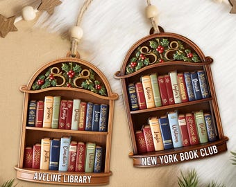 Peut inclure: Deux ornements en bois en forme d'étagères à livres, avec les inscriptions "AVELINE LIBRARY" et "NEW YORK BOOK CLUB". Chaque ornement présente des livres miniatures avec des noms comme Daniel et Olivia. Des feuilles de houx et des baies ornent le dessus.