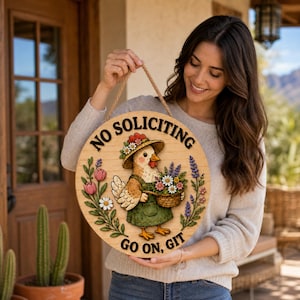 May include: Round wooden sign with a cartoon chicken wearing a hat and holding a basket of flowers. The sign reads "NO SOLICITING" and "GO ON, GIT" in black text. The sign is decorated with floral elements and has a rope for hanging.