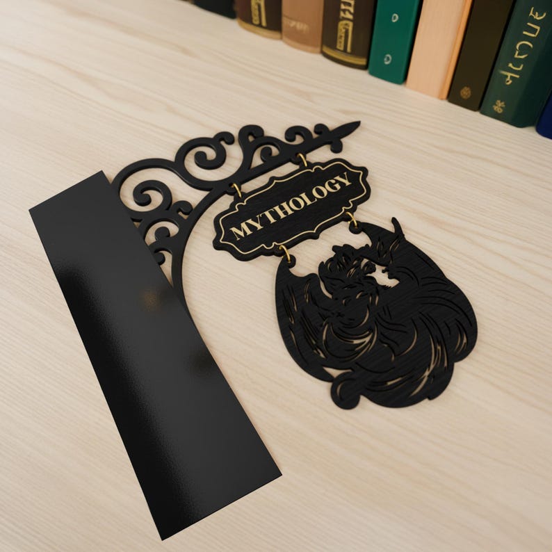 以下が含まれることがあります： 金色の文字で「MYTHOLOGY」と書かれた黒い金属製の看板。看板は装飾的なスクロールデザインと神話上の生き物のシルエットが特徴です。黒い長方形の物体が看板に寄りかかっています。