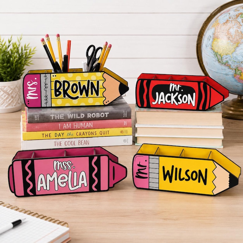May include: Four colorful pencil and crayon-shaped desk organizers. One yellow pencil organizer reads "BROWN" and another reads "WILSON". A red crayon organizer reads "JACKSON" and a pink crayon organizer reads "AMELIA".