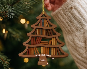May include: Wooden Christmas tree ornament shaped like a bookshelf, filled with miniature books in various colors. The ornament has the text "Book Club Name" and "2025" on it. A gold string is attached for hanging.