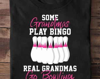 May include: Black t-shirt with the text "Some Grandmas Play Bingo, Real Grandmas Go Bowling" in white and pink. The design includes white bowling pins with pink accents.