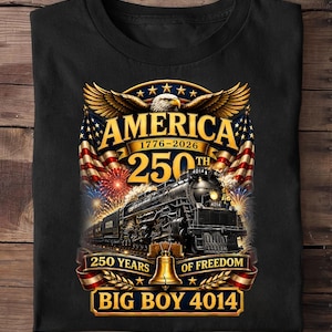 May include: A black t-shirt featuring a graphic of a steam locomotive, the Big Boy 4014, with an American eagle, flags, and fireworks. Text includes AMERICA 1776-2026, 250TH, 250 YEARS OF FREEDOM, and BIG BOY 4014, centered around a golden bell icon.