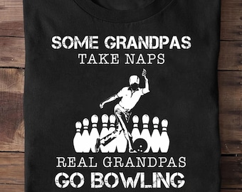 May include: Black t-shirt with white text and a bowling graphic. The text reads "SOME GRANDPAS TAKE NAPS REAL GRANDPAS GO BOWLING (THEN TAKE A NAP)". The graphic shows a bowler and bowling pins.